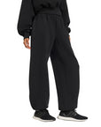 Vista laterale del pantalone Adidas donna nero, dettaglio della silhouette ampia e del tessuto spacer vellutato con modal